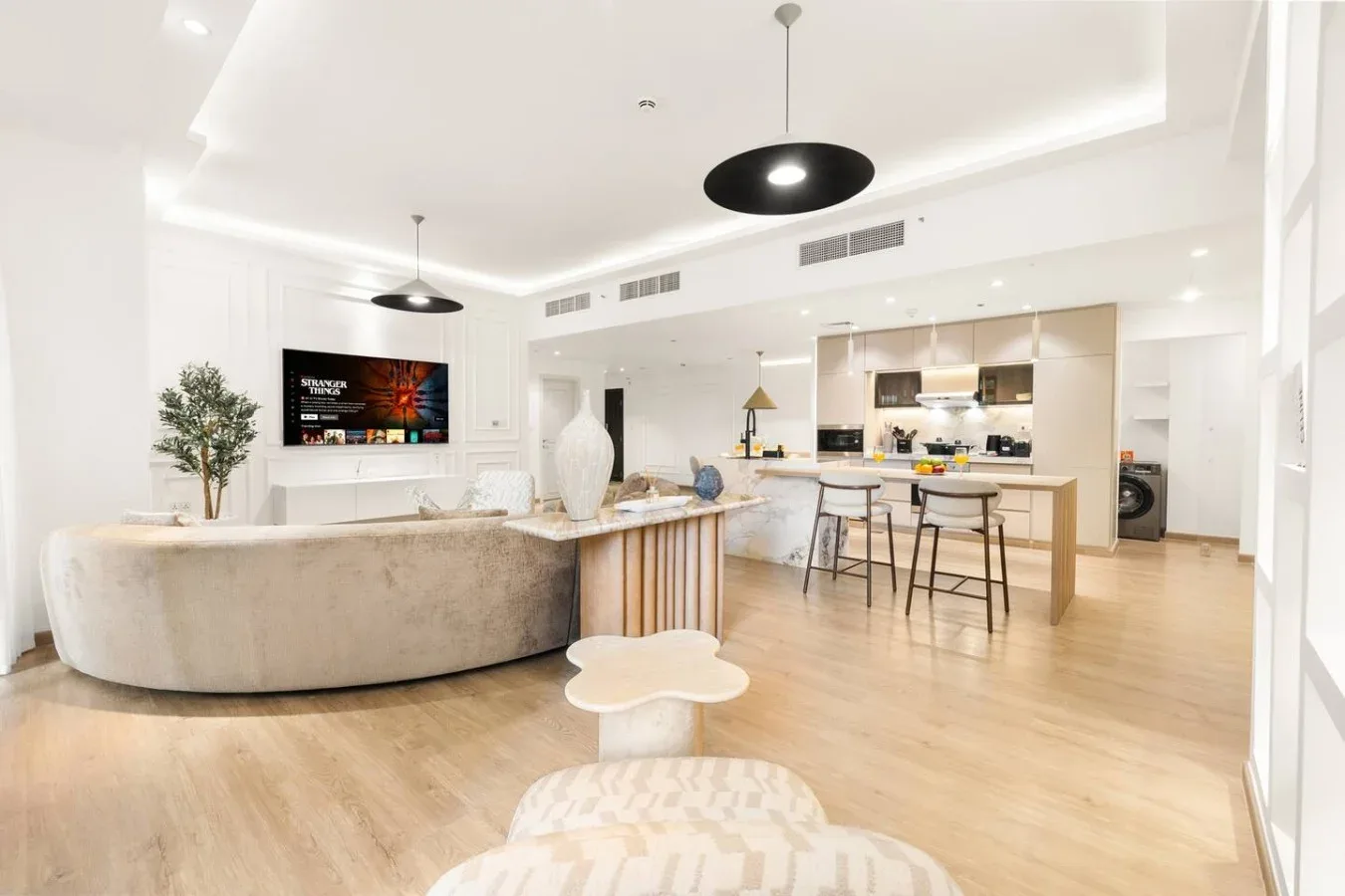 A bright open-plan living room and kitchen with a curved sofa and island.
