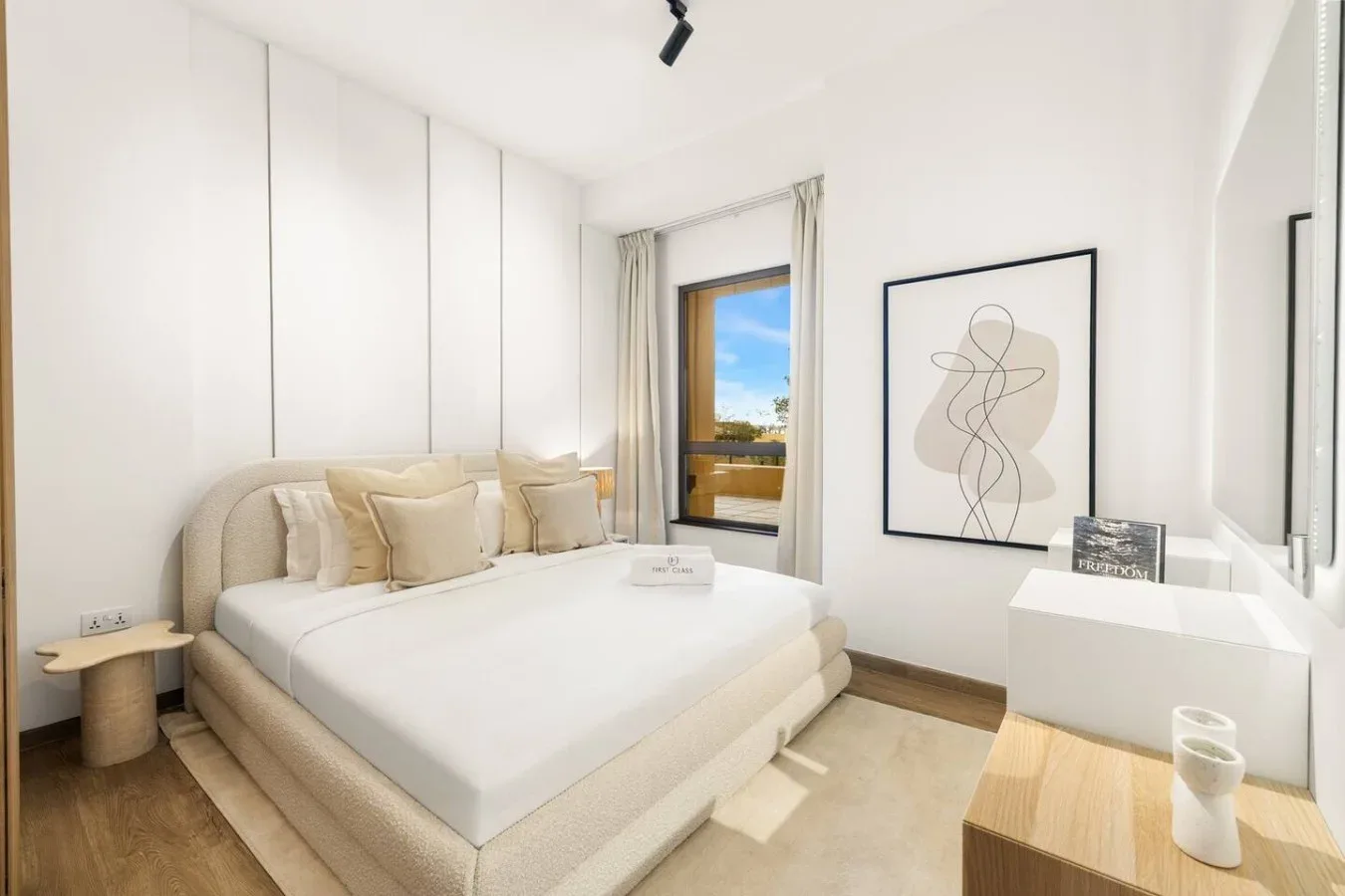 A bright bedroom with a large bed, abstract wall art, and a window.