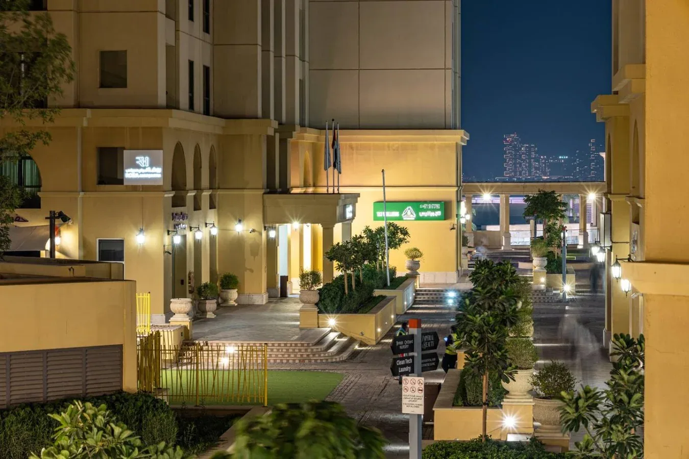 A nighttime view of a landscaped building entrance with illuminated walkways.