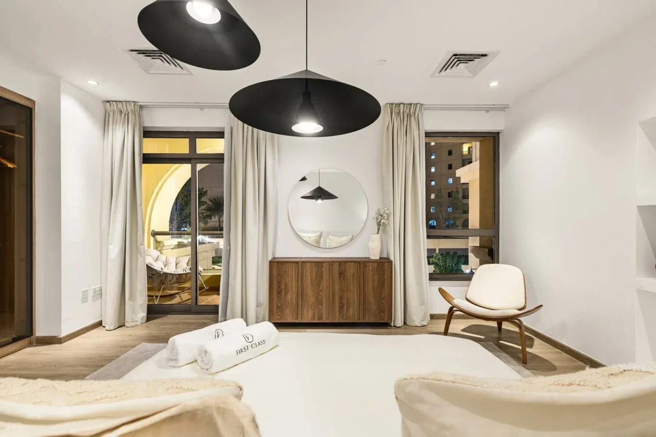 A bright sitting room with a wooden console and round wall mirror.