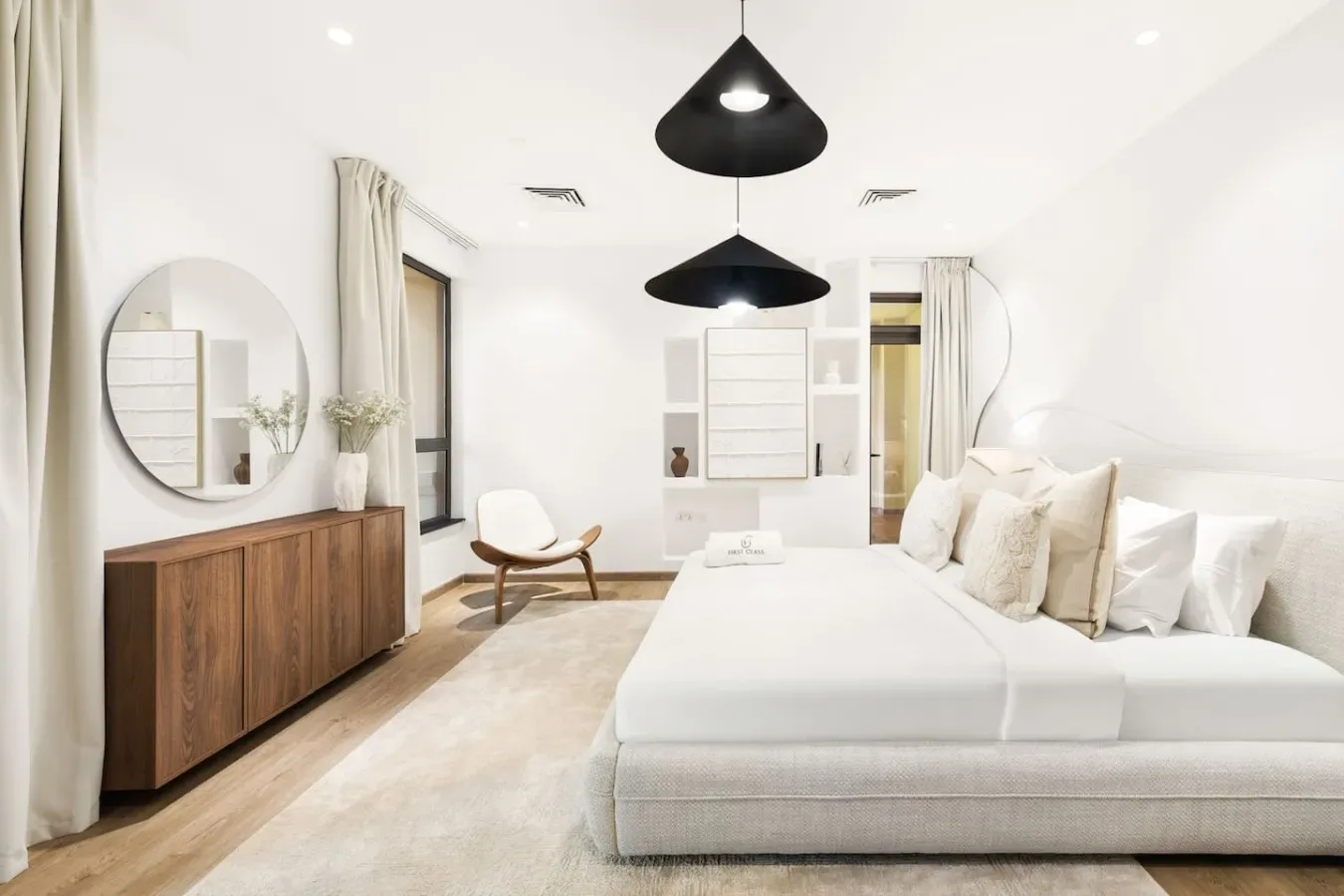 Un dormitorio luminoso con una cama grande, un mueble de madera y lámparas colgantes.