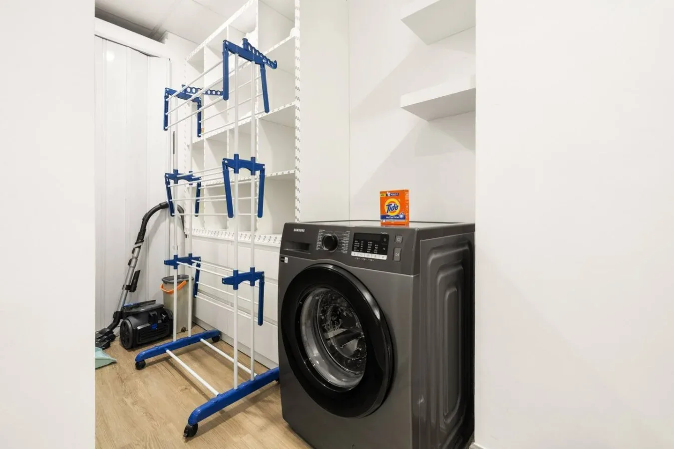 A laundry area with a washing machine and a freestanding drying rack.
