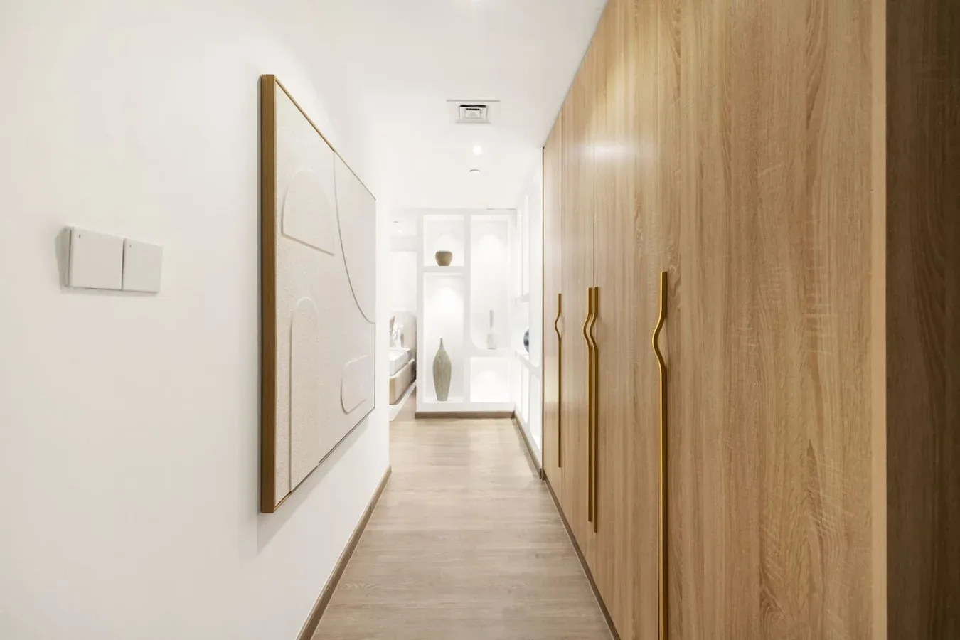 A bright hallway with built-in wooden cabinets and framed wall art.