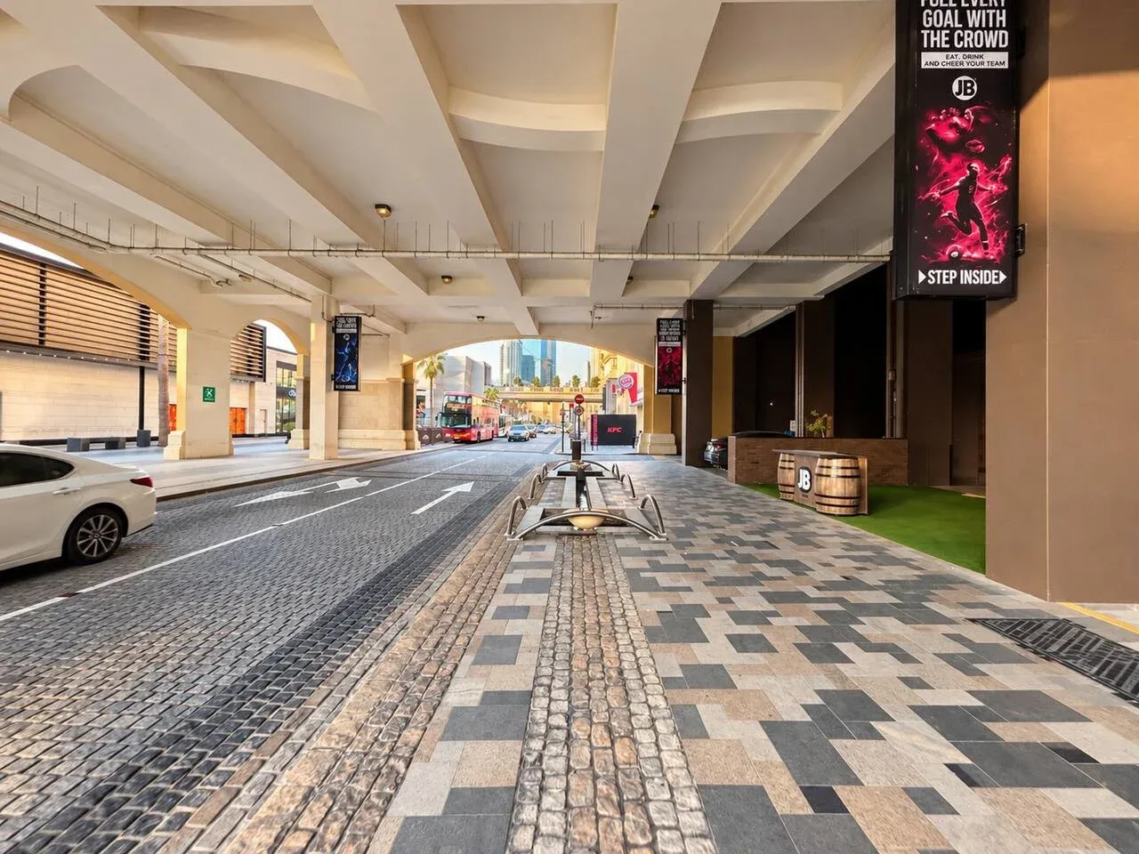 A covered urban street with a paved sidewalk and vehicles.