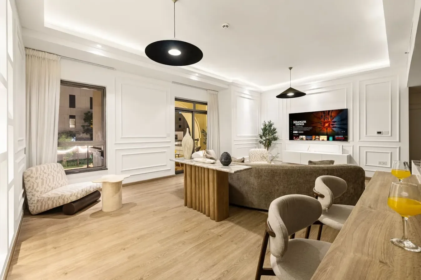 A bright living room with a dining table, seating, and a television.