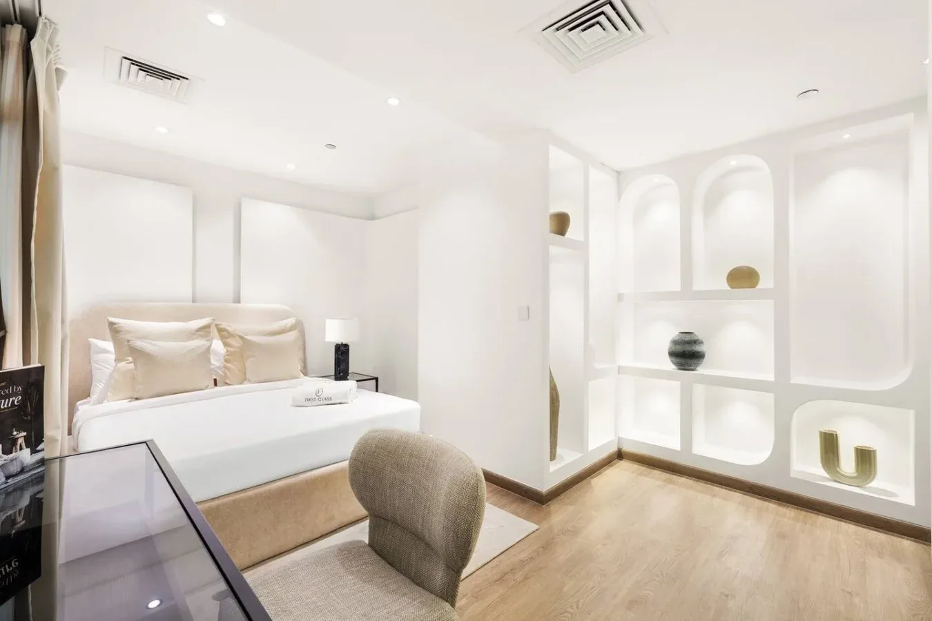 A bright bedroom with a neatly made bed and built-in display shelves.