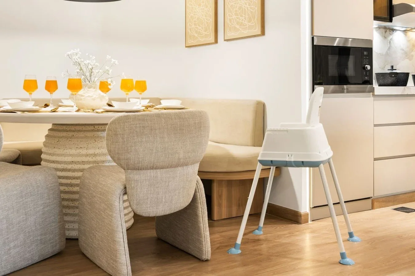 A dining area with a set table and a high chair beside the kitchen.