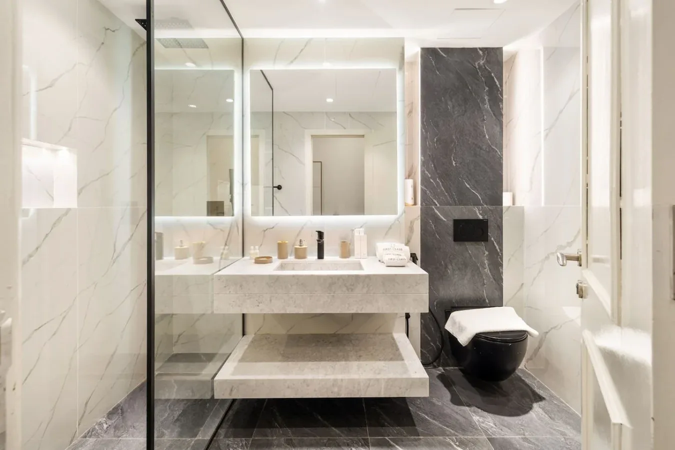 A bright bathroom with a floating sink, large mirror, and toilet.