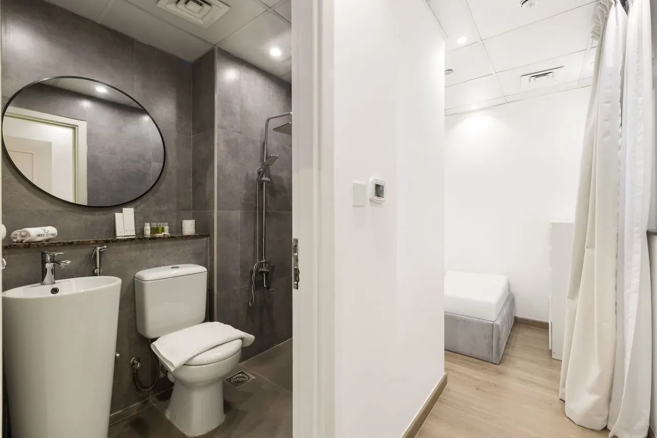 A bathroom with a sink and toilet opens onto a small bedroom area.