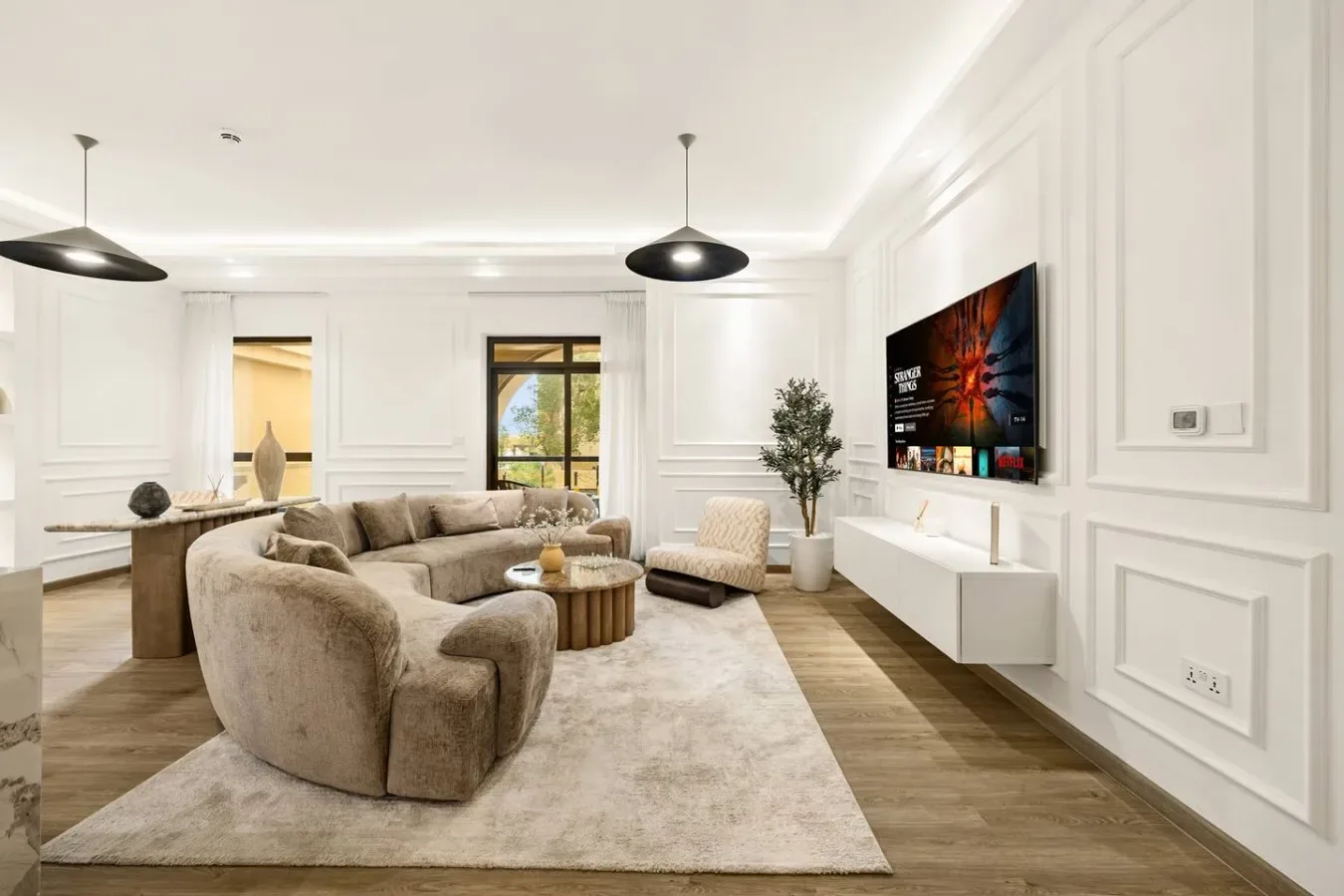 Una sala luminosa con asientos alrededor de una mesa baja y un televisor montado en la pared.