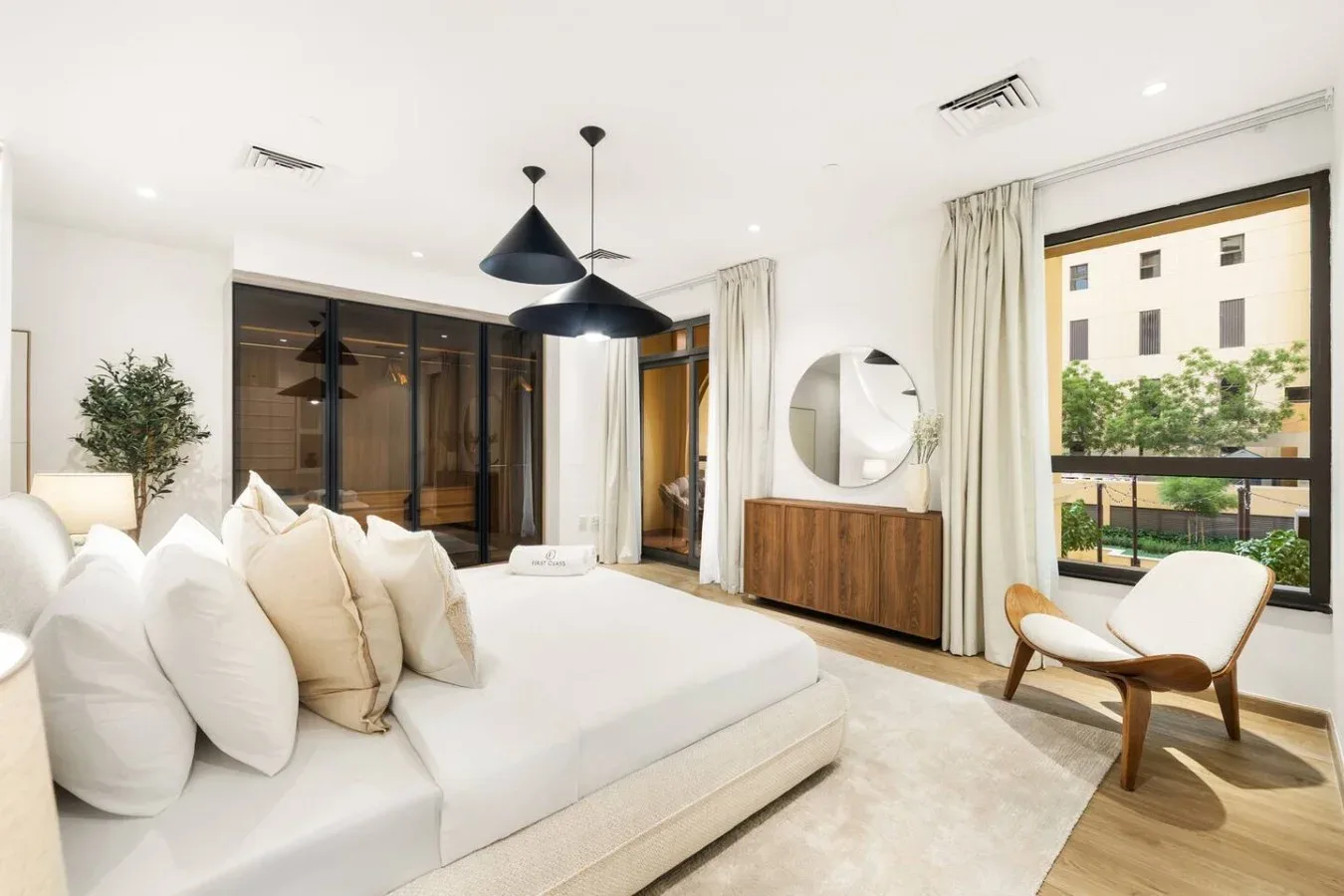 A bright bedroom with a bed, pendant lights, and a large window.