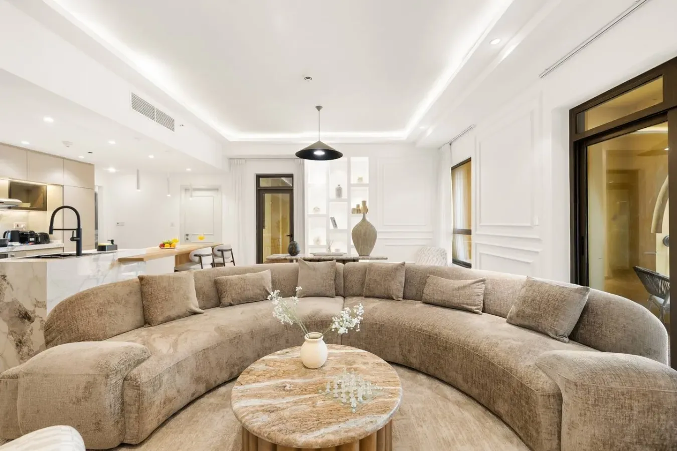 A bright living room with curved seating and an open kitchen.