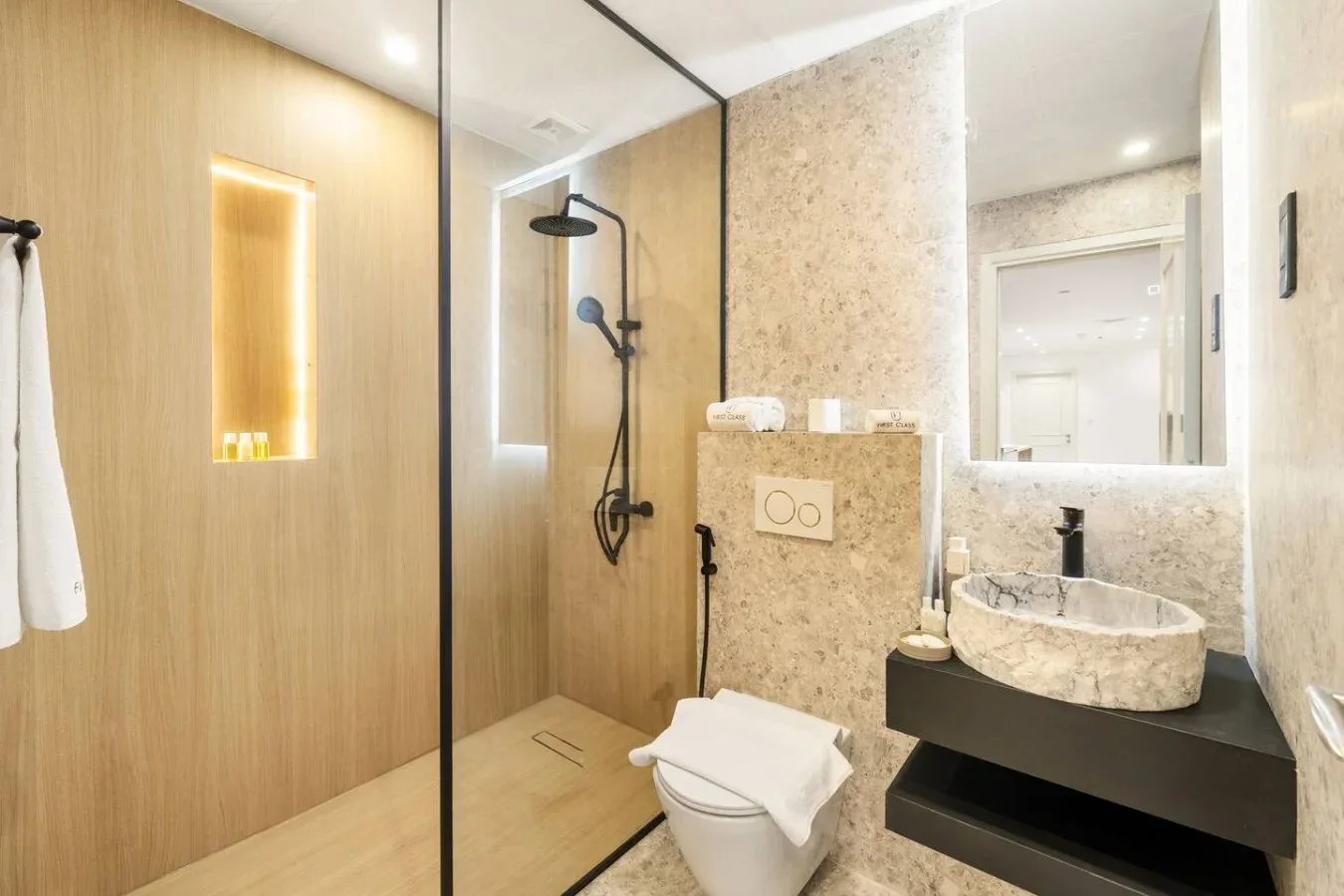 A modern bathroom with a glass shower and a stone-look vanity.