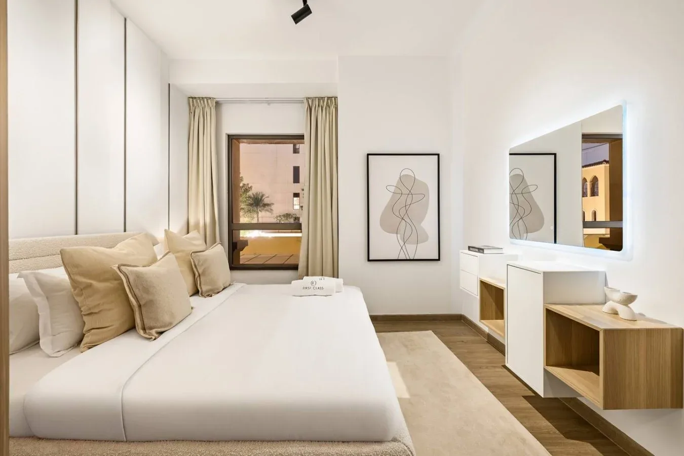 A bright bedroom with a large bed, a window, and a wall mirror.