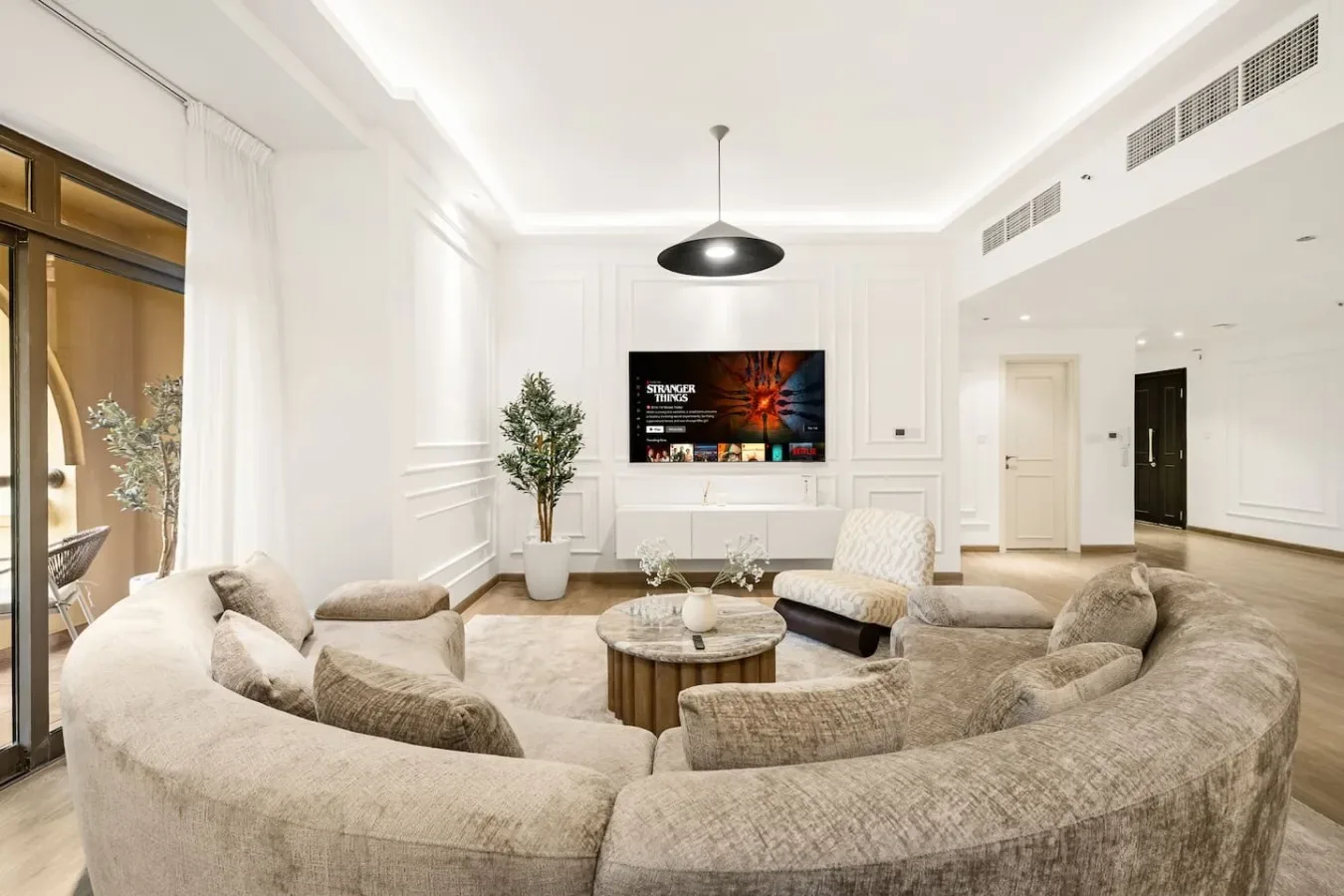 A bright living room with curved seating arranged around a coffee table and television.