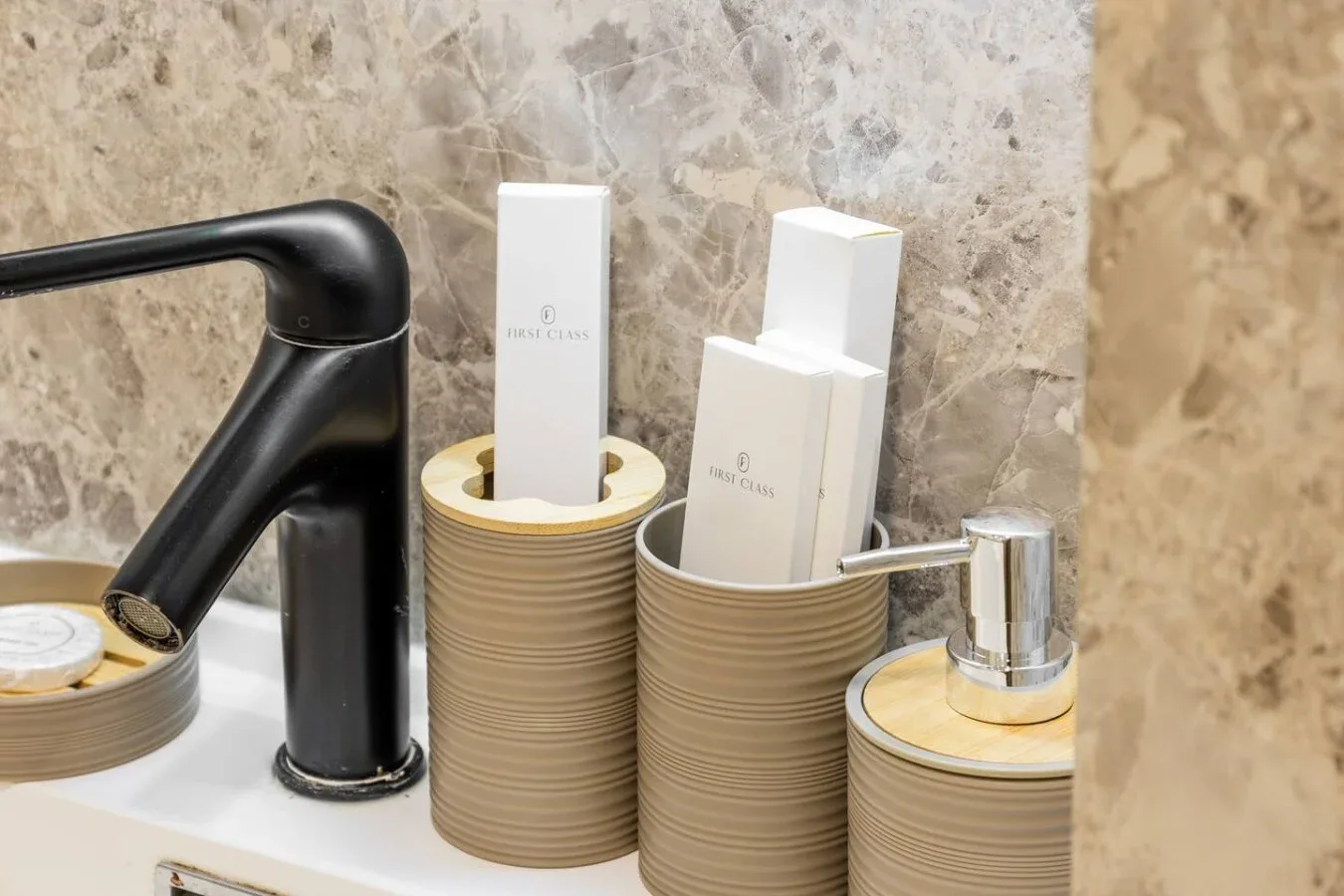 Bathroom sink area with a black faucet and toiletries arranged on the counter.