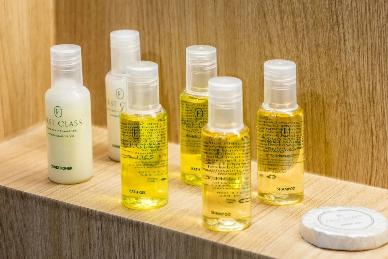 Small toiletry bottles and a wrapped soap sit on a wooden counter.