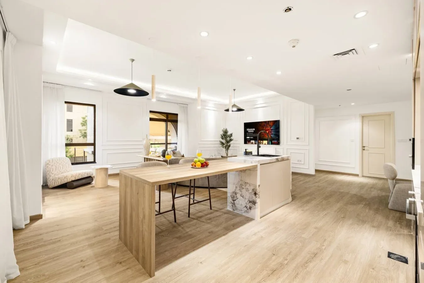 A bright open kitchen and dining area with a long island and light wood floors.