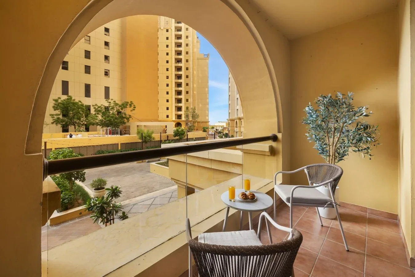 A balcony seating area overlooks nearby buildings and landscaped grounds.