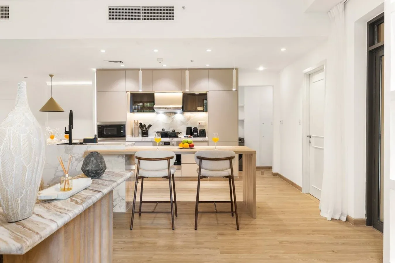 A bright open kitchen with a central island and two stools.