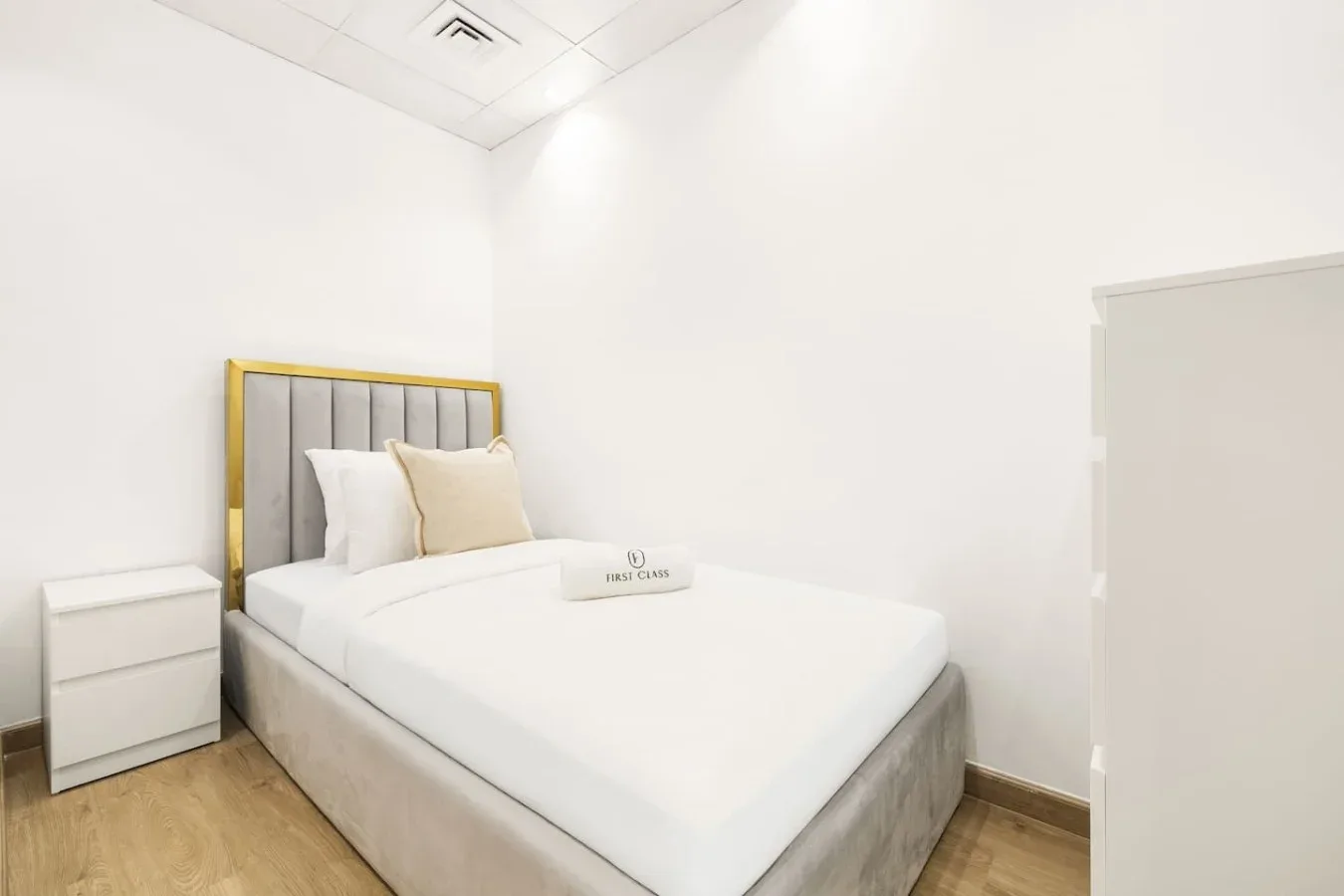 A bright bedroom with a neatly made bed and a small bedside table.