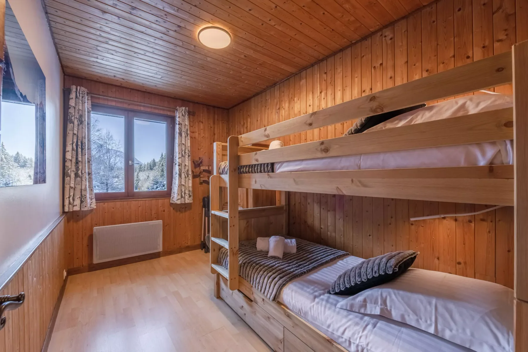 Un dormitorio revestido de madera con literas y una ventana.