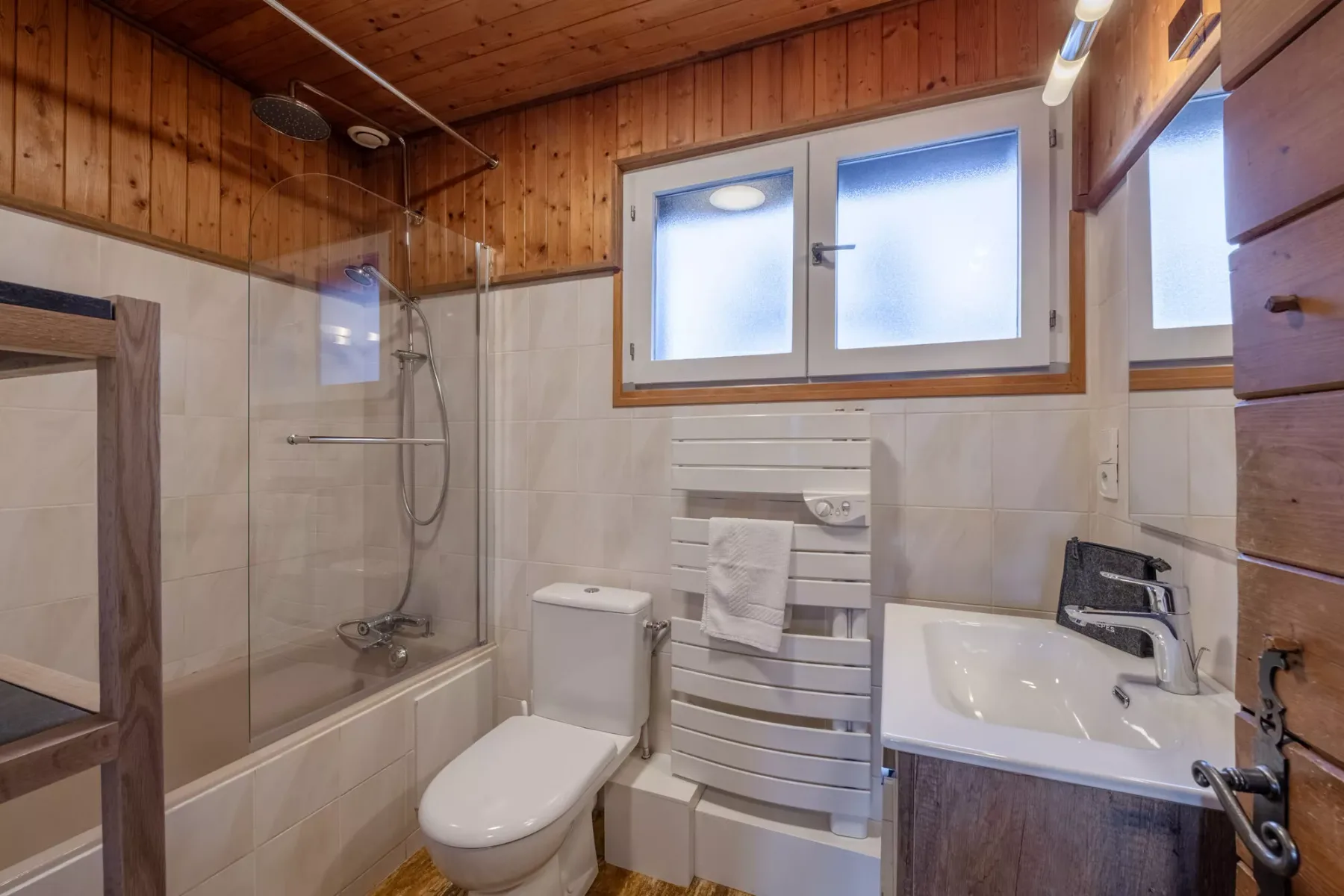 Un baño con bañera, inodoro y lavabo bajo una ventana.