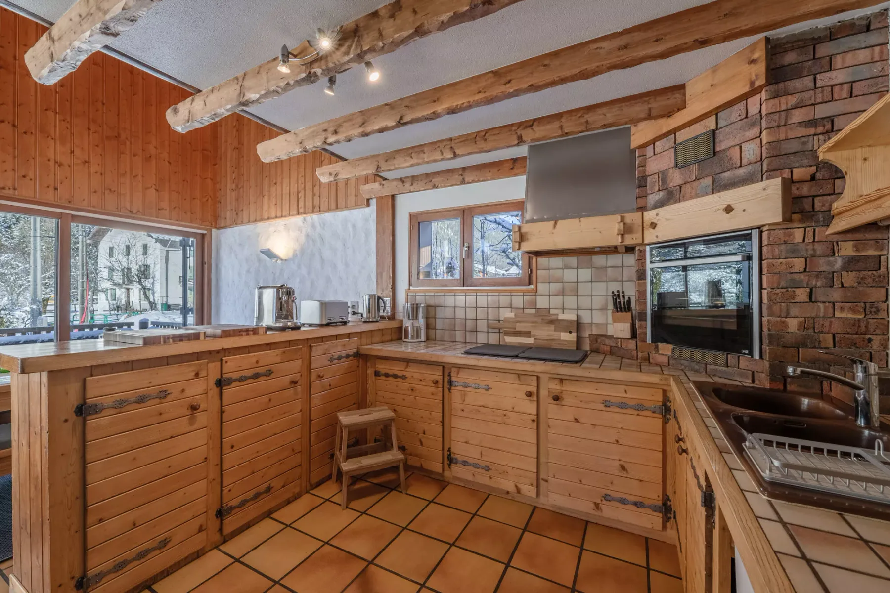 Una cocina revestida de madera con encimeras, vigas expuestas y una chimenea de ladrillo.