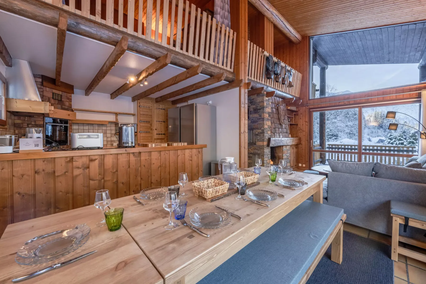 Comedor de madera con una mesa larga, asientos y una cocina abierta.