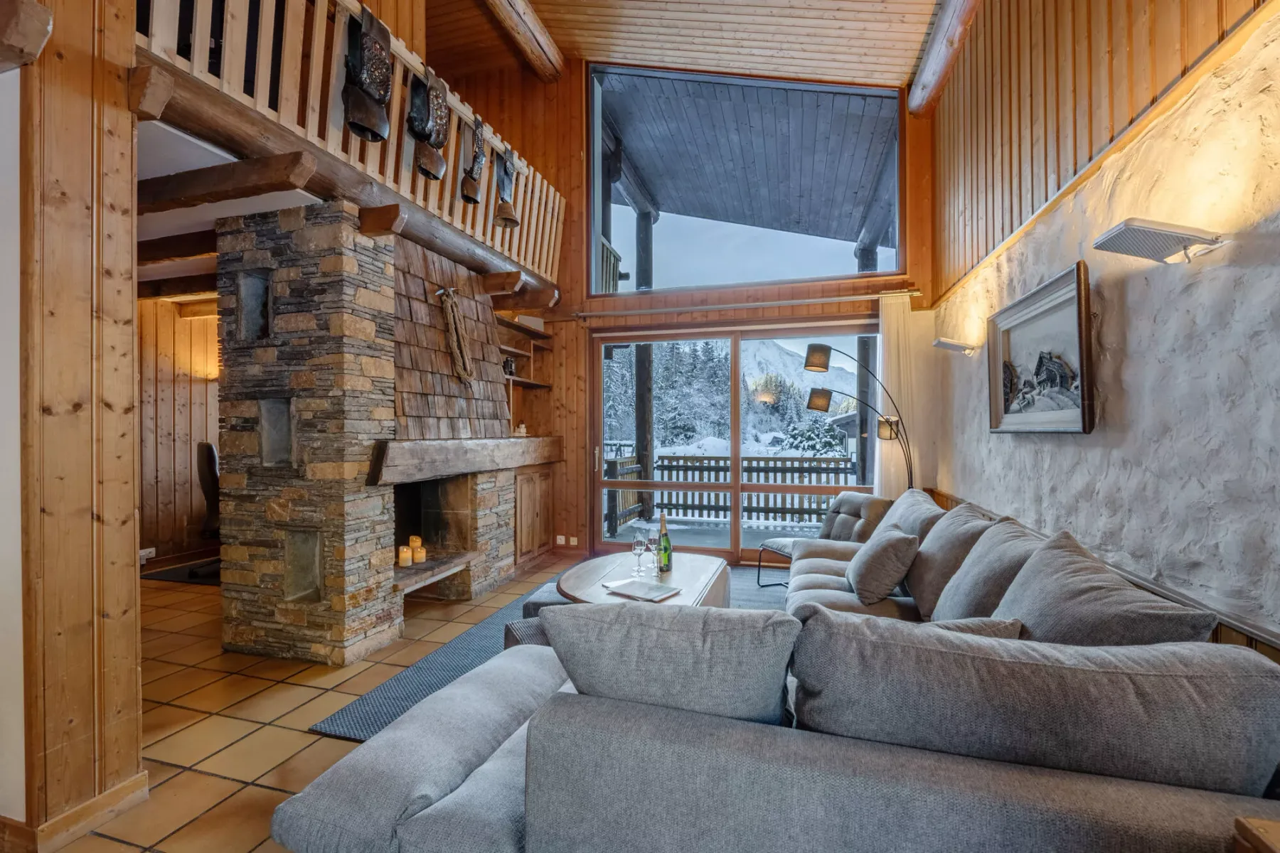 Una sala de estar revestida de madera con chimenea de piedra y grandes ventanas.