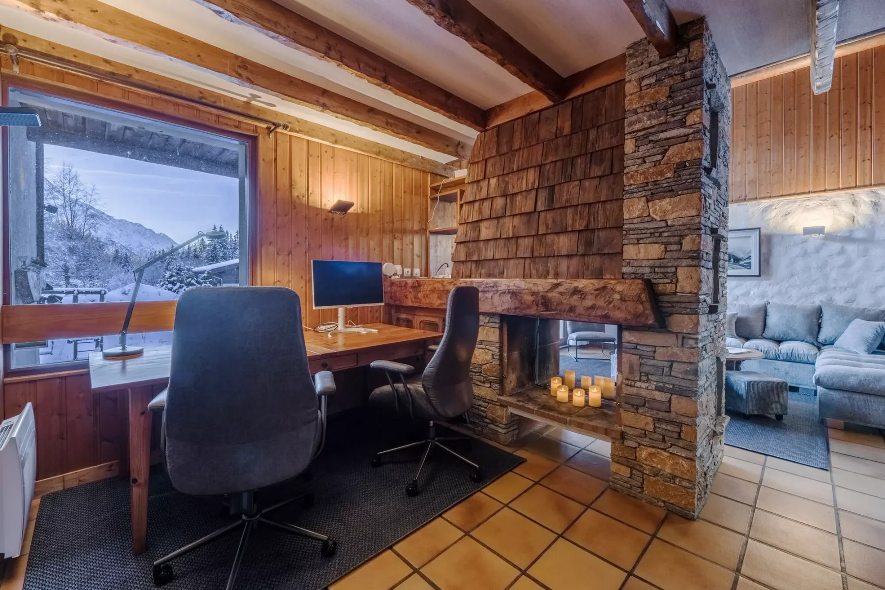 Una sala revestida de madera con escritorio y asientos junto a una chimenea de piedra.