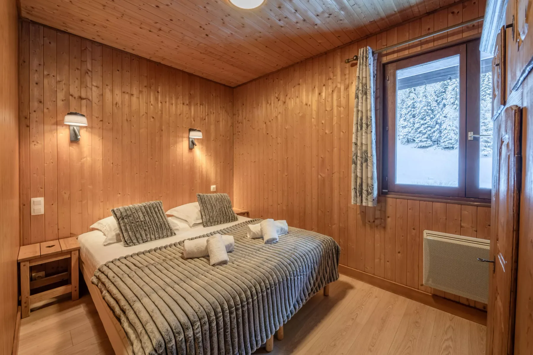 Un dormitorio revestido de madera con una cama junto a una ventana.