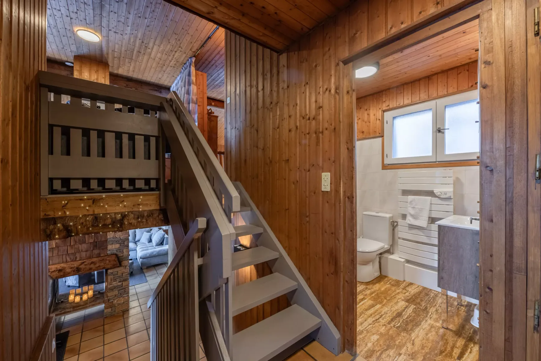 Un interior revestido de madera con escaleras junto a un baño abierto.