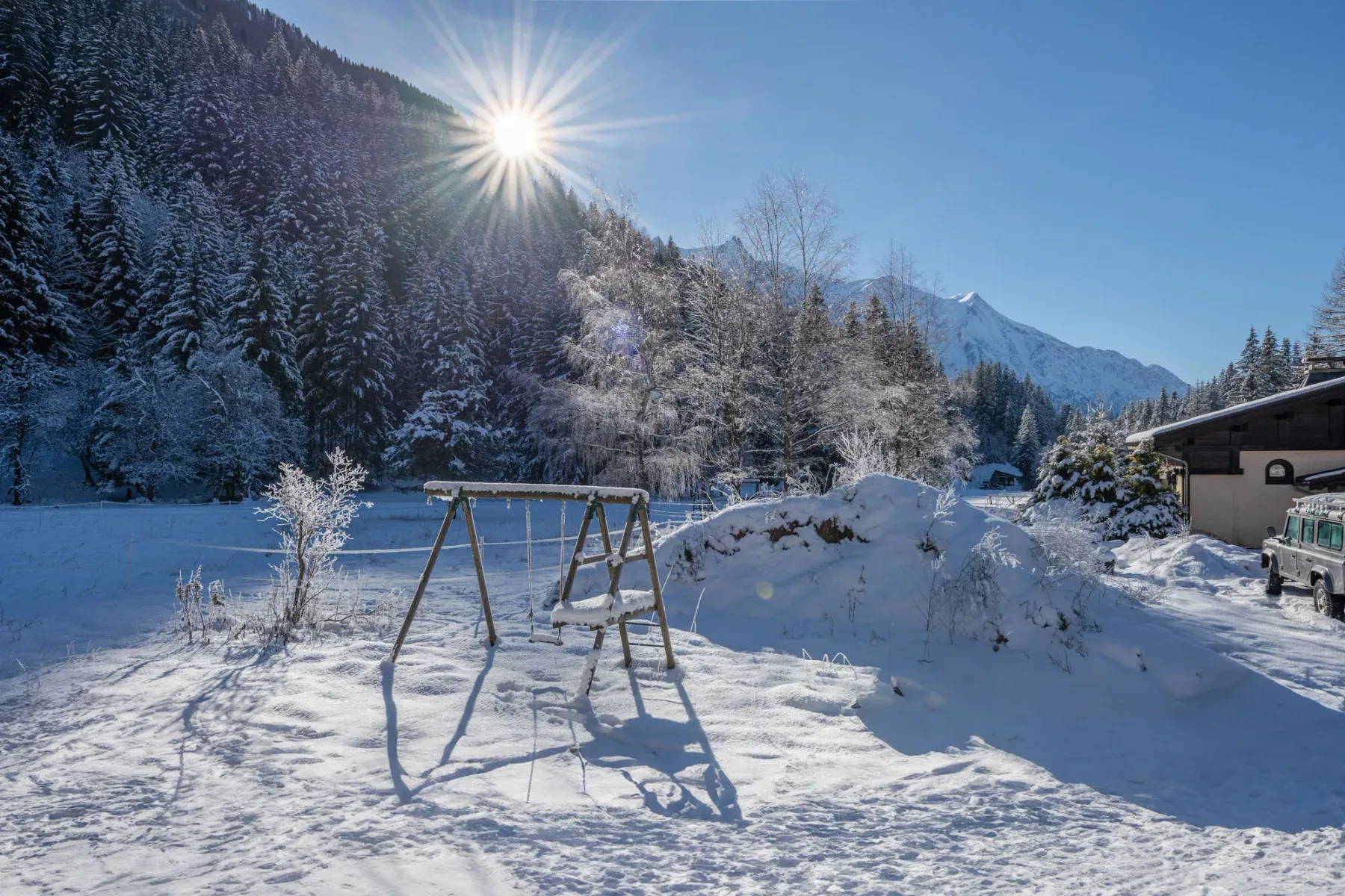 Una zona de juegos al aire libre cubierta de nieve, con un columpio bajo el sol de montaña.