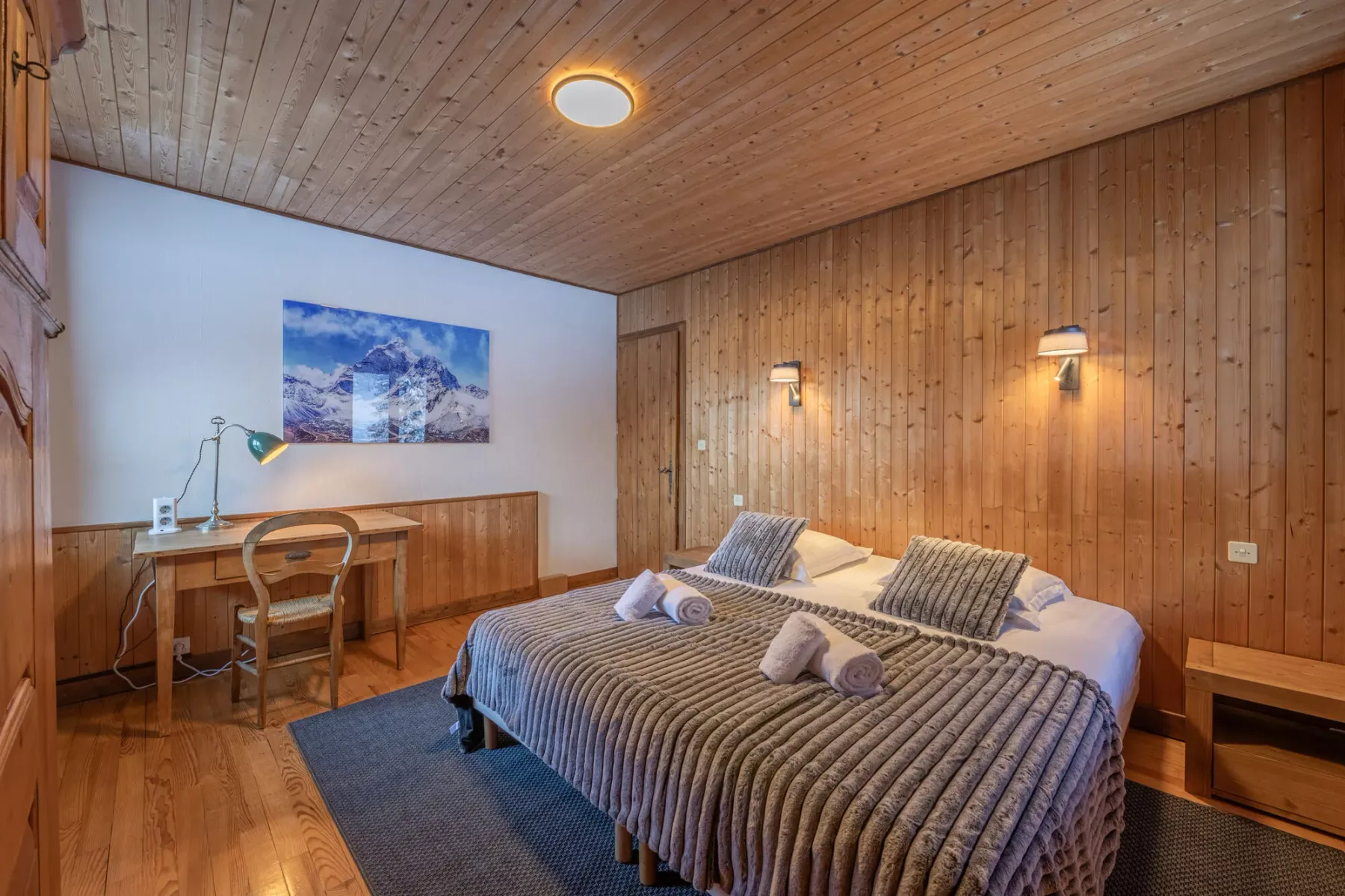 Un dormitorio con dos camas, un escritorio y paredes revestidas de madera.
