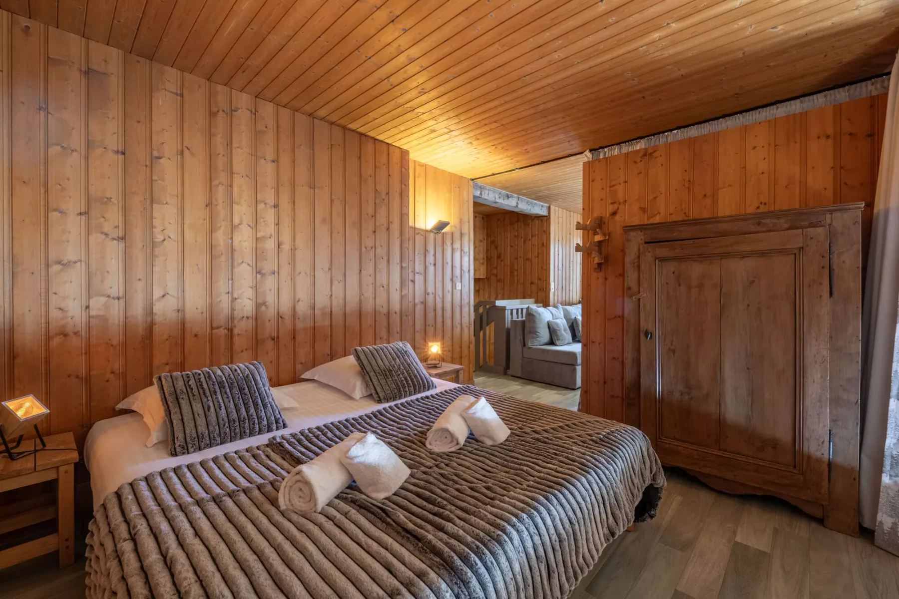 Un dormitorio revestido de madera, con una cama grande y una zona de estar al fondo.