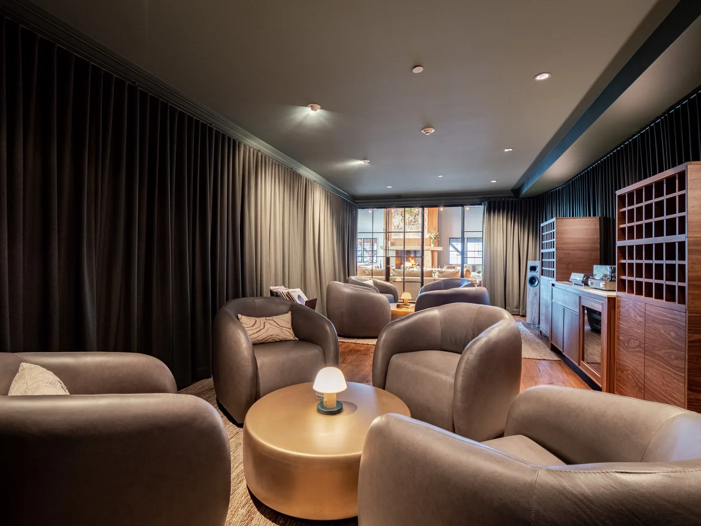 A lounge with upholstered seating, a round table, and floor-to-ceiling curtains.