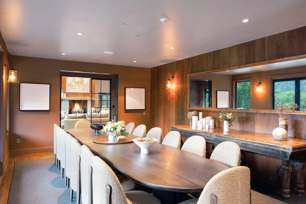 A dining room with a long table and upholstered seating.