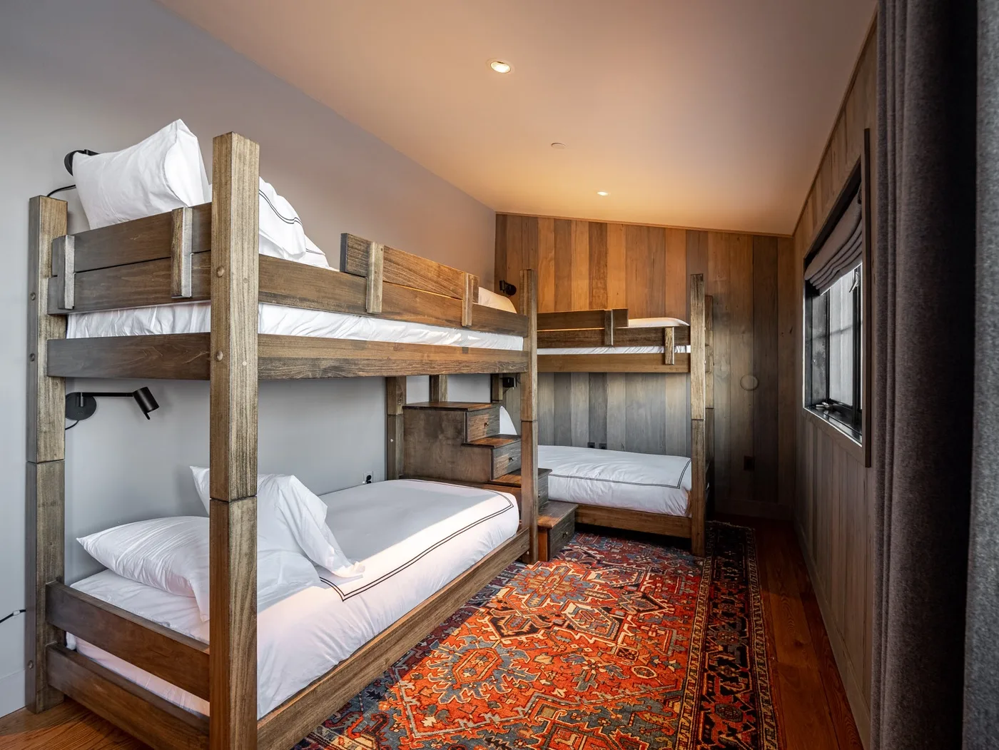 A wood-paneled bunk room with built-in beds and a colorful patterned rug.