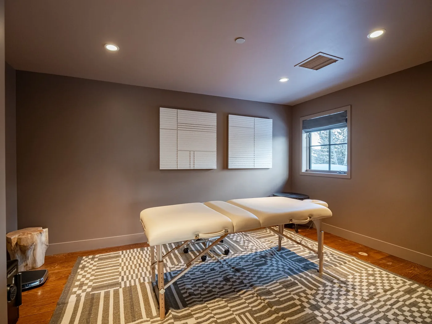A treatment room with padded tables, a patterned rug, and wall-mounted panels.