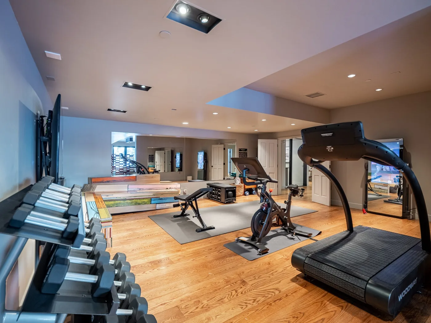 A fitness room with exercise equipment, weights, and treadmills.