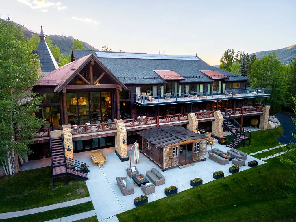 A large lodge-style building overlooks a paved patio with outdoor seating.