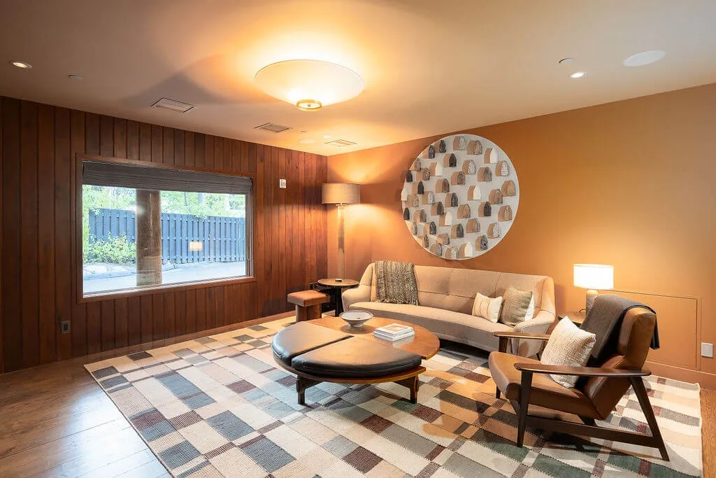 A warm-toned lounge with seating around a coffee table and a patterned rug.