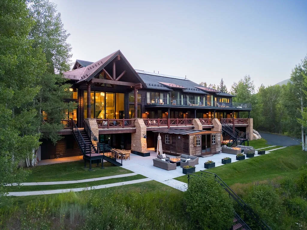 A large lodge-style building sits among trees beside a landscaped lawn.