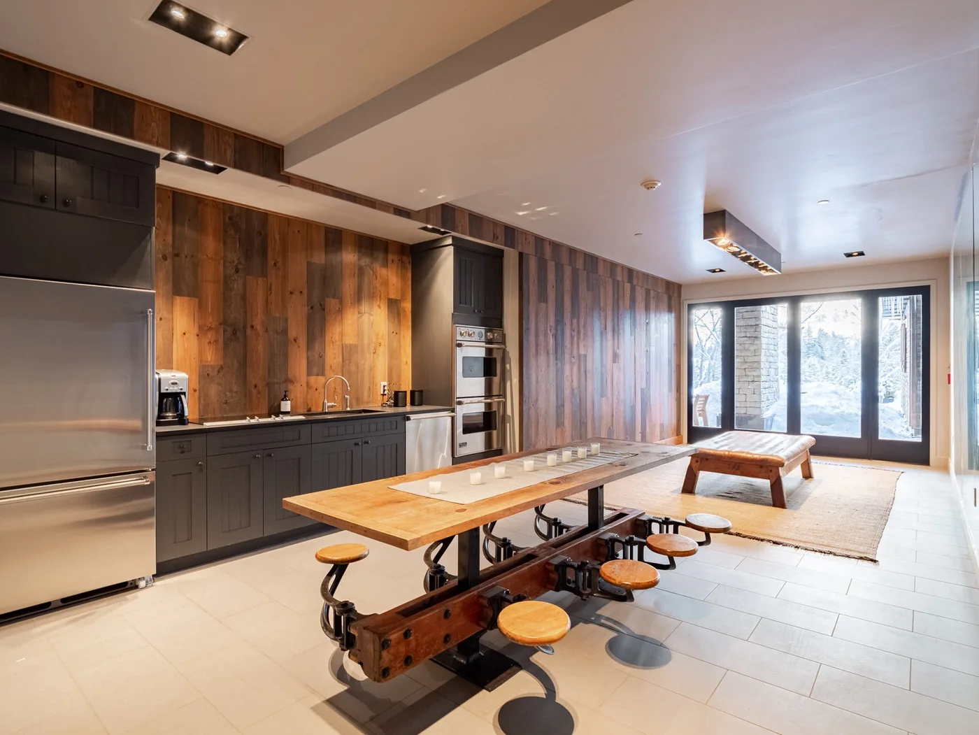 A spacious kitchen and dining area with a long wooden table and large windows.