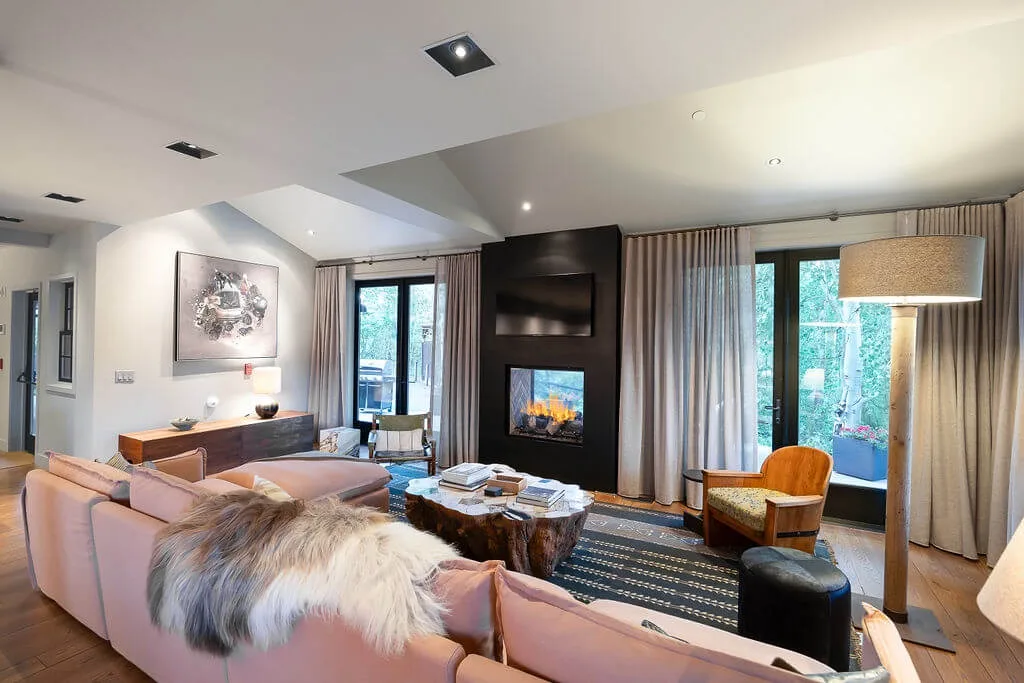 Living room with seating arranged around a fireplace and large windows.