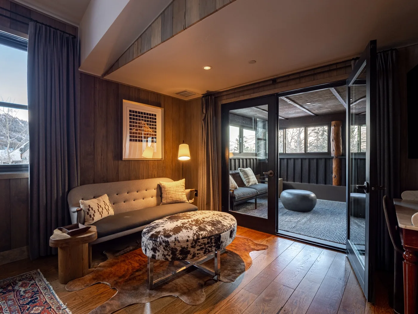 A wood-paneled sitting room with a sofa and glass doors opening onto a covered patio.