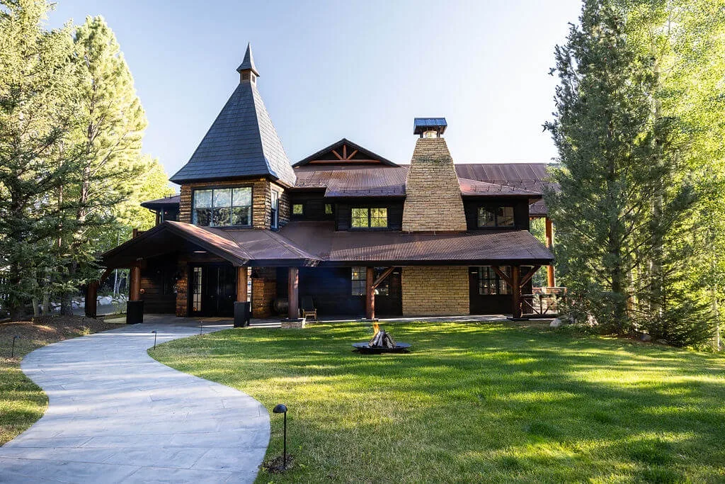 A large lodge-style house stands behind a curved walkway and green lawn.