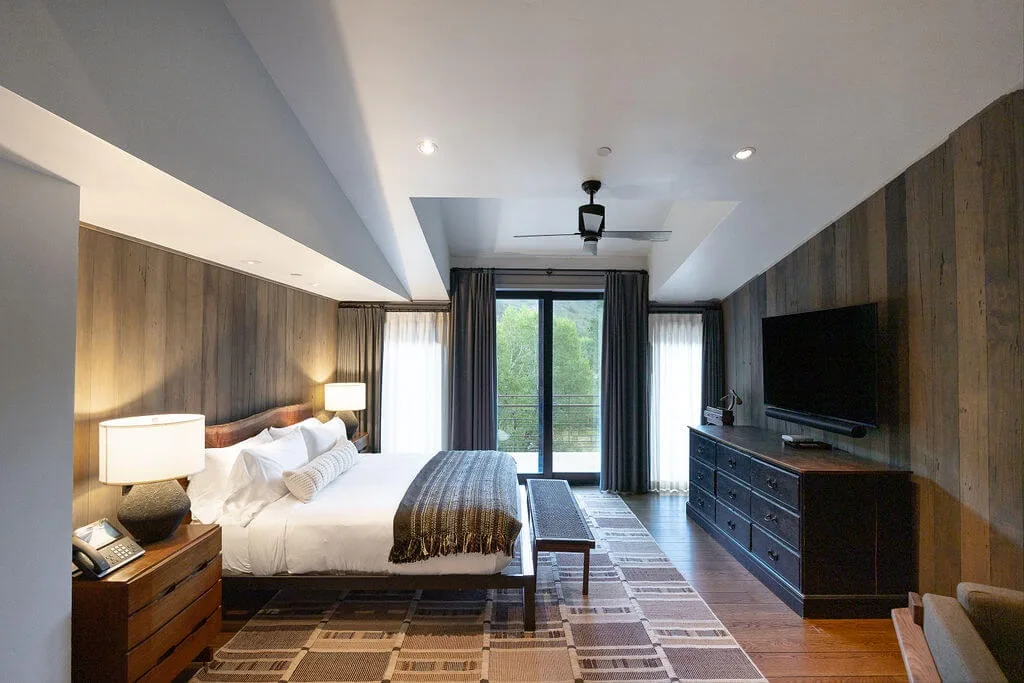 A bedroom with a bed, bedside lamps, and a television on a dresser.