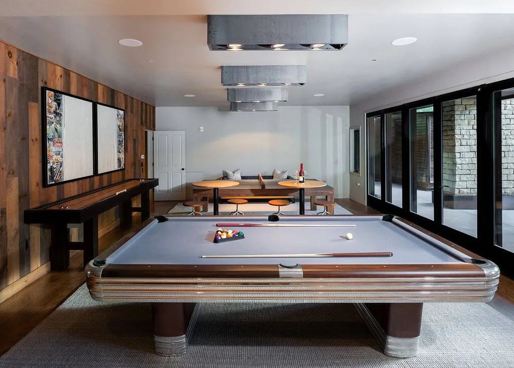A game room with a pool table and a dining table in the background.